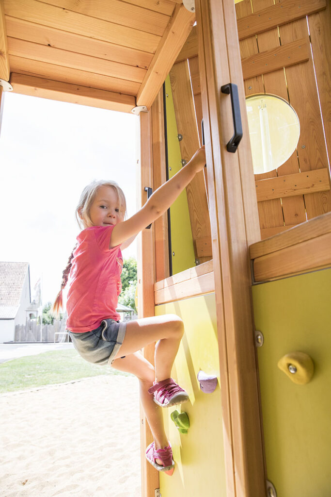 Climbing for children - A girl is climbing up the outside of a play structure.