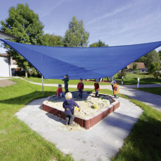 Sandpit with sunshade – Blue sun sail stretched over sandpit with playing children.
